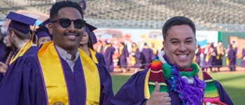 two SF State students wearing graduation gowns at AT&T arena